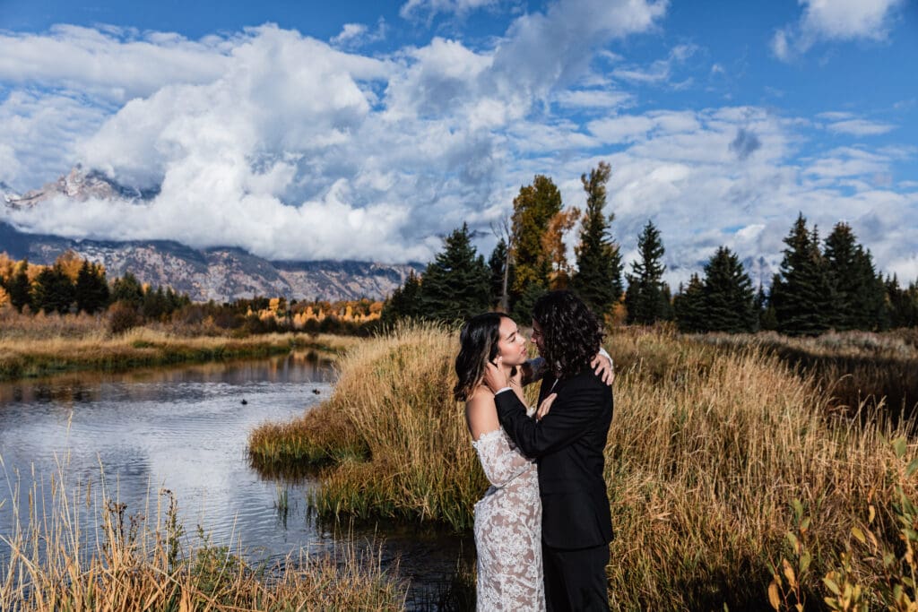 Snow-capped Grand Teton peaks reflected in a quiet mountain lake surrounded by golden reeds during fall at Schwabacher Landing.