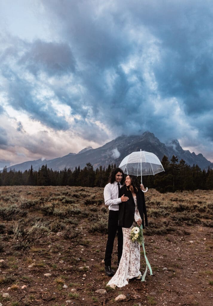 Couple sharing a quiet, intimate moment with dramatic Grand Teton mountain peaks behind them at Cascade Canyon Turnout.