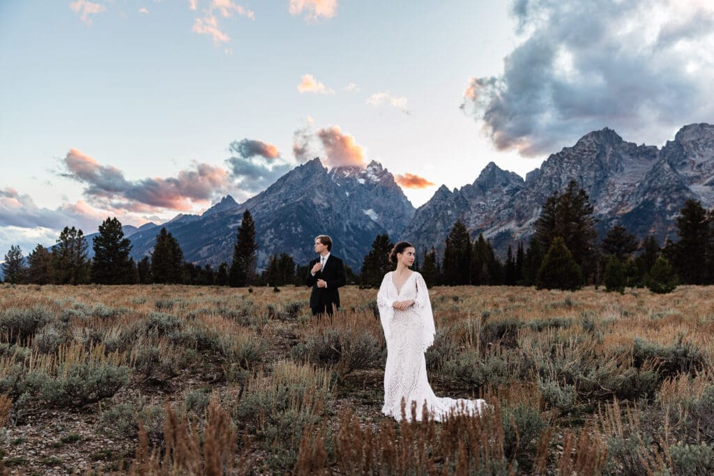 Couple sharing a romantic moment during golden hour with snow-capped Grand Teton mountains in the background at Grand Teton National Park.
