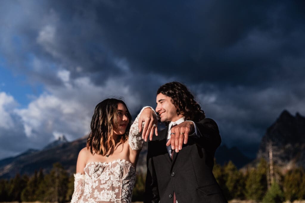 Elopement couple celebrating and showing off their wedding bands in Grand Teton National Park, surrounded by alpine scenery.