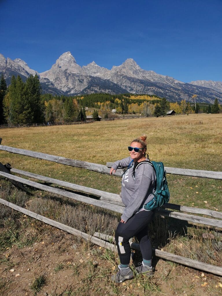 Photographer posing at the start of Delta Lake trail in Grand Teton National Park, surrounded by alpine scenery and rugged peaks.