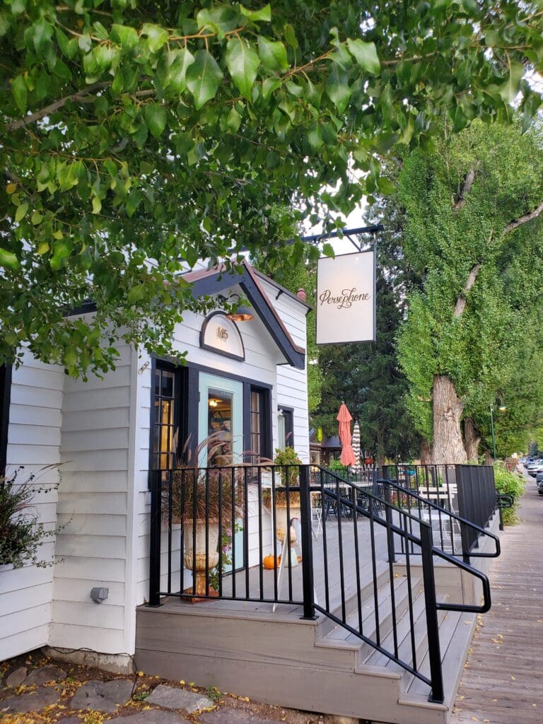 Wooden boardwalk lined with green trees near park buildings on a sunny day in Grand Teton National Park.