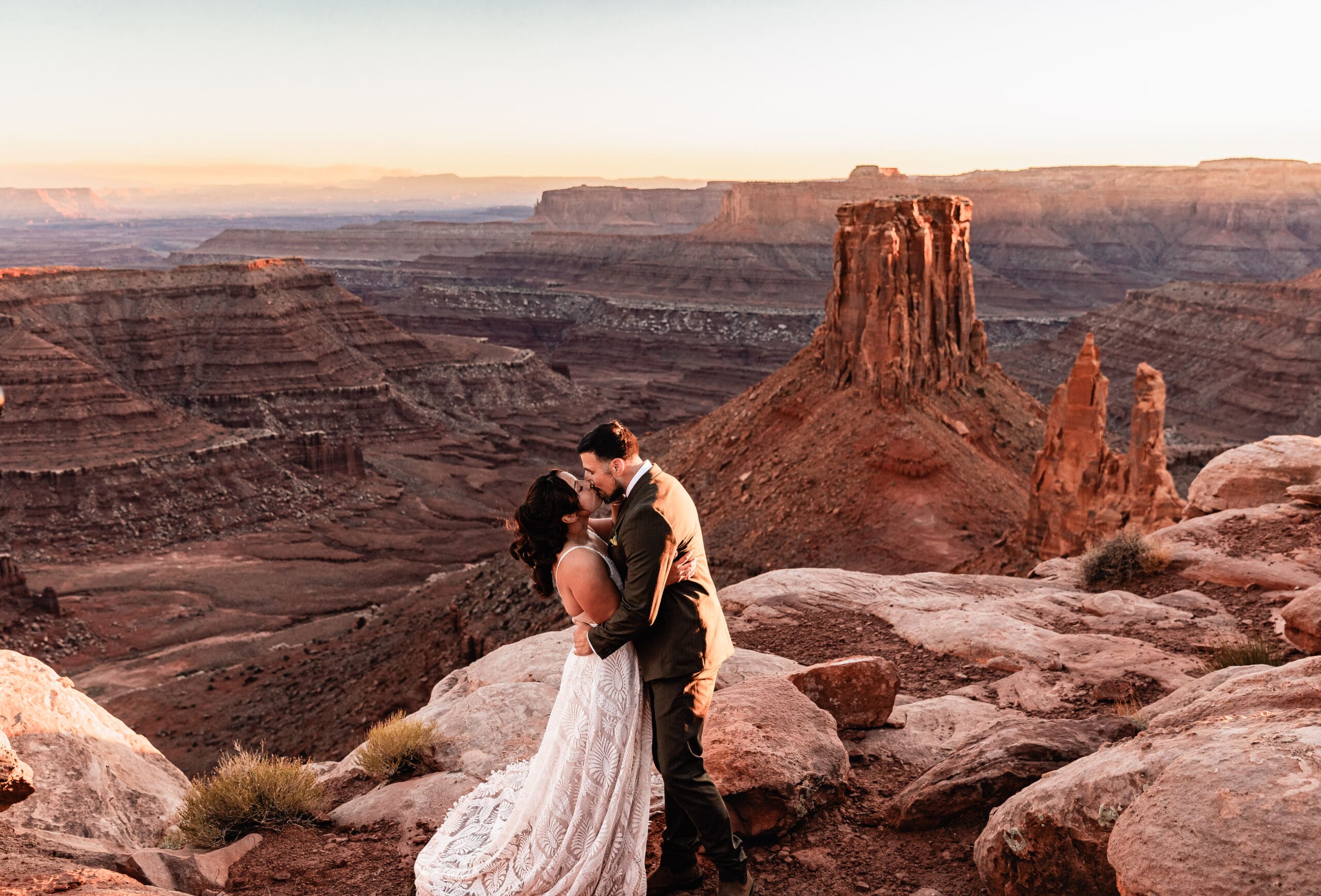 Elopement couple sharing a quiet kiss with dramatic desert scenery at Marlboro Point in Moab, Utah.