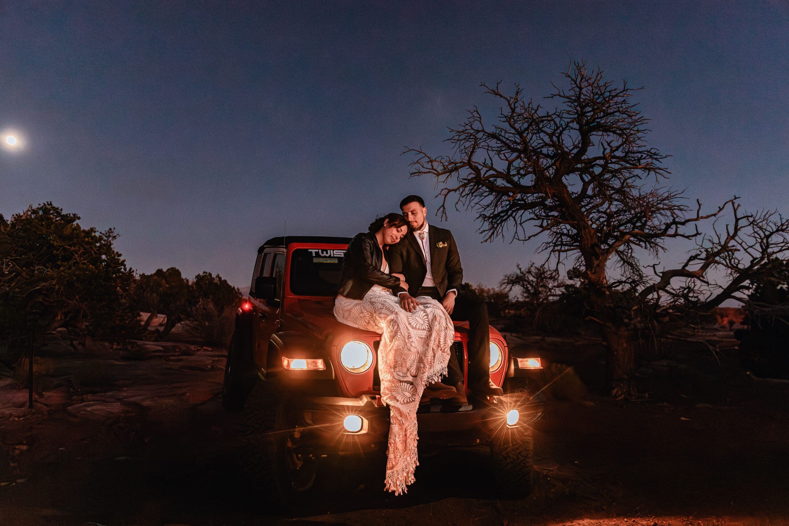 ouple sitting together on a Jeep in Moab, Utah, enjoying a relaxed moment during their intimate desert elopement.