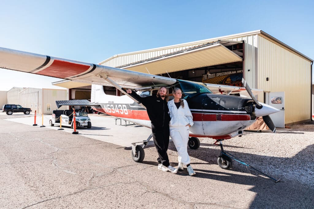 Elopement couple posing beside the Skydive Moab airplane, capturing the start of their adventurous wedding day in the Utah desert.