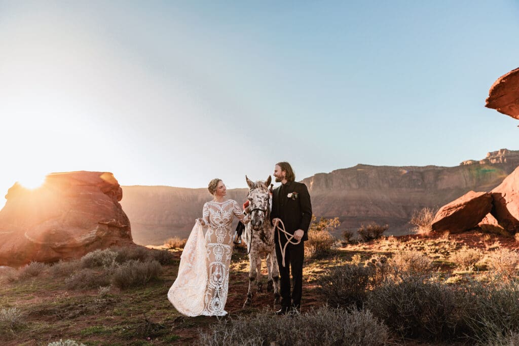 Bride and groom posing alongside their horse at golden hour during their Moab elopement at Hauer Ranch.