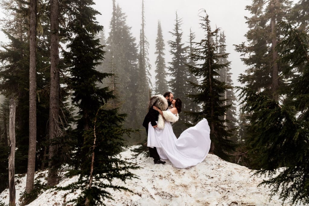 Bride and groom sharing a kiss as the bride’s dress train lifts in the mountain breeze at Reflection Lake, Mount Rainier National Park.