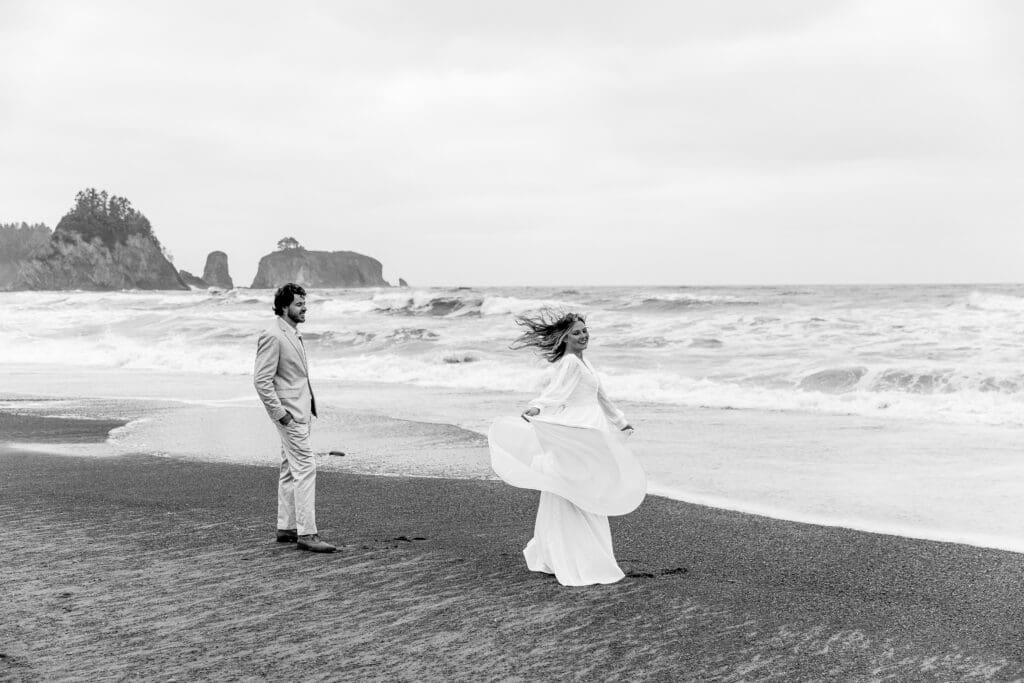 Bride and groom chasing each other along the shoreline during their whimsical Rialto Beach elopement in Washington