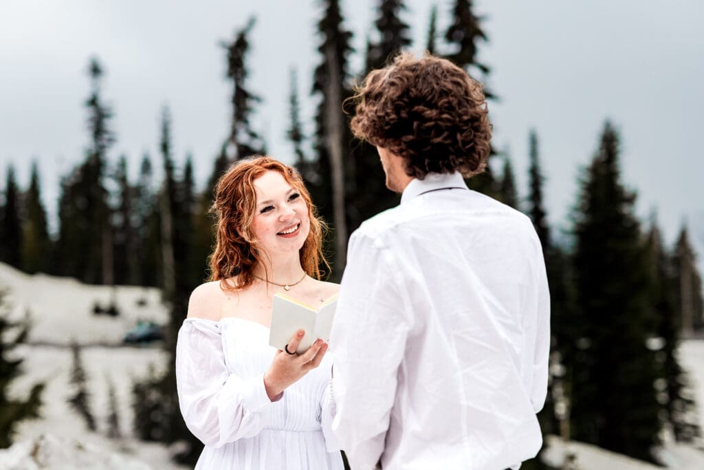 Bride reading her wedding vows with serene Tipsoo Lake and pine trees in the background at Mount Rainier National Park.