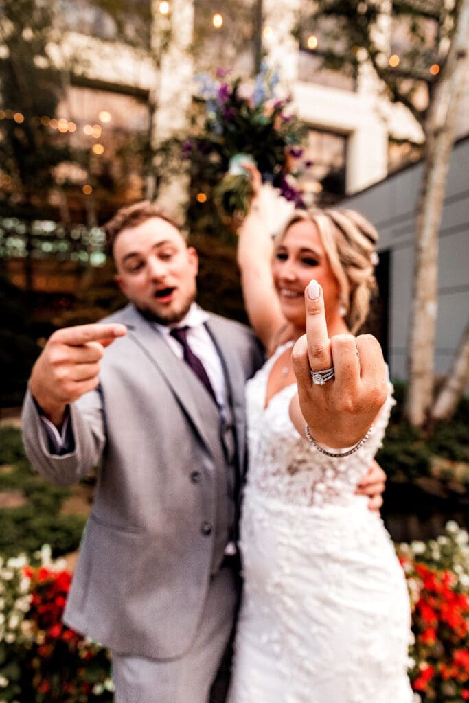 Bride holding up ring finger as couple celebrates during Pittsburgh Airport Marriott portraits