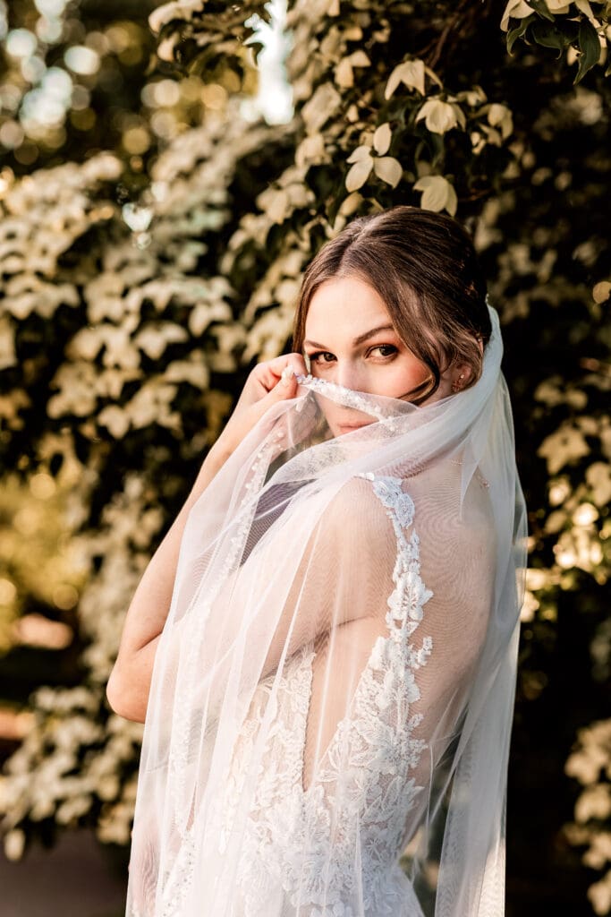 Pittsburgh bride standing with veil draped over her face looking at the camera during outdoor portraits at Phipps Botanical Gardens