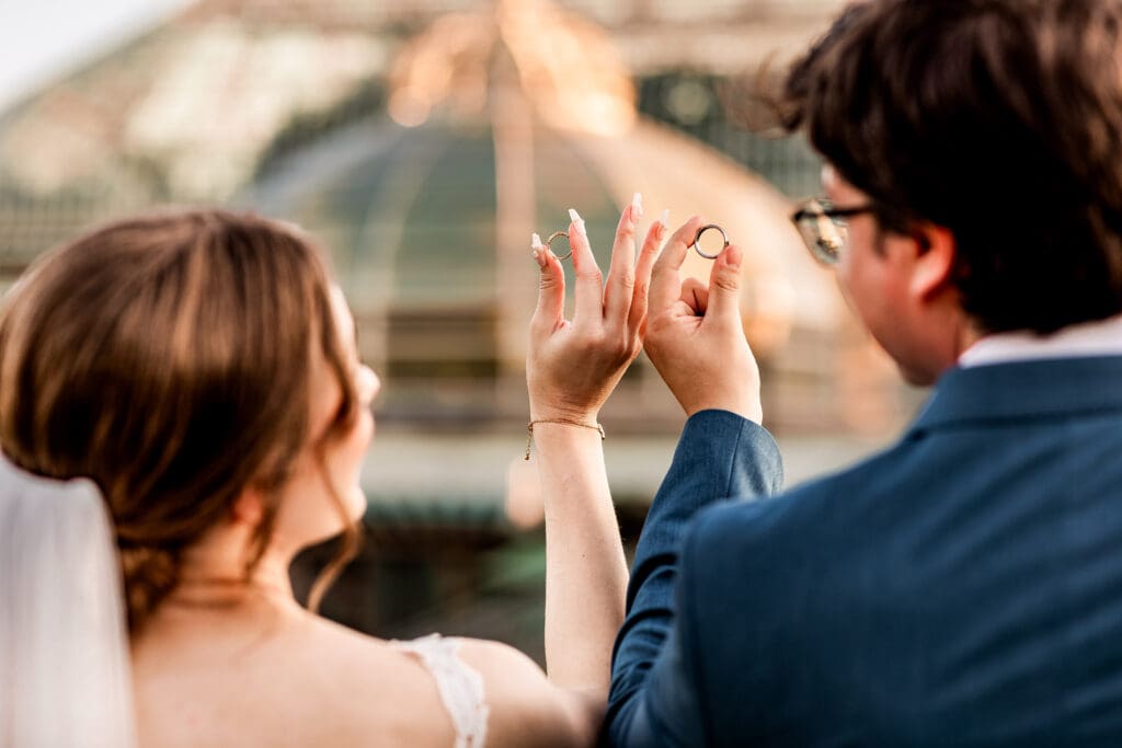 Close-up of wedding bands with bride and groom blurred in the background at Phipps Botanical Gardens