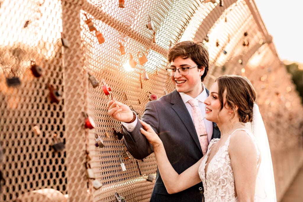 Pittsburgh couple attaching their lock to the Locks of Love bridge during golden hour at Phipps Botanical Gardens