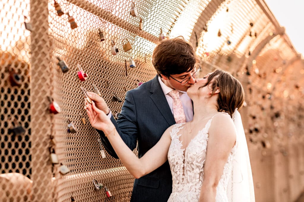 Pittsburgh bride and groom kissing in front of their lock on the Locks of Love bridge at golden hour