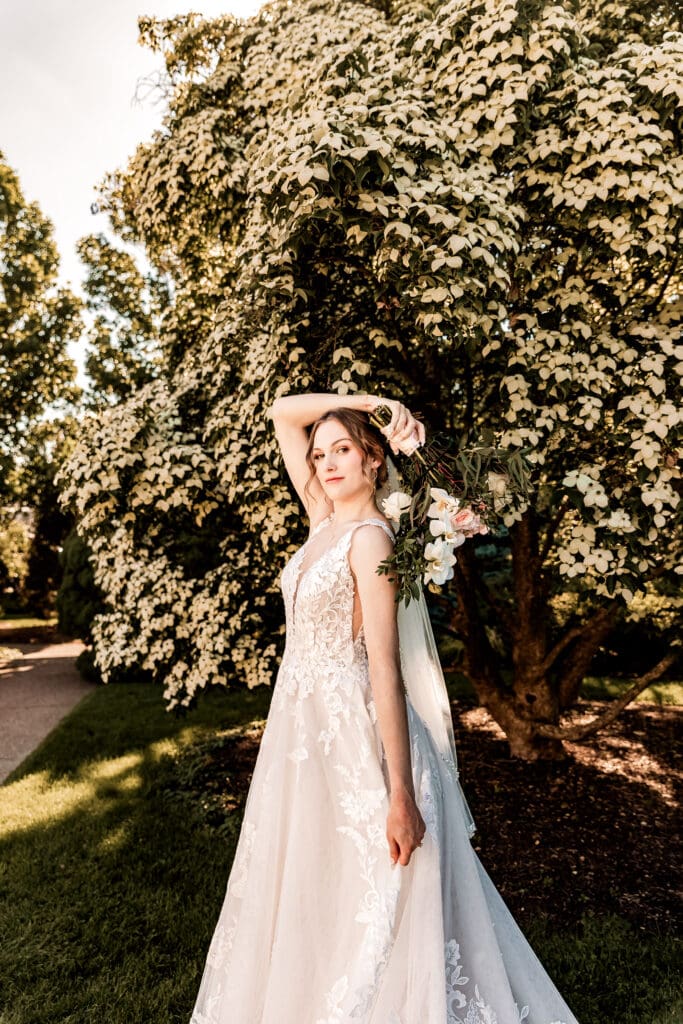 Pittsburgh bride standing under a Dogwood tree, swishing her wedding dress during a Phipps Botanical Gardens wedding