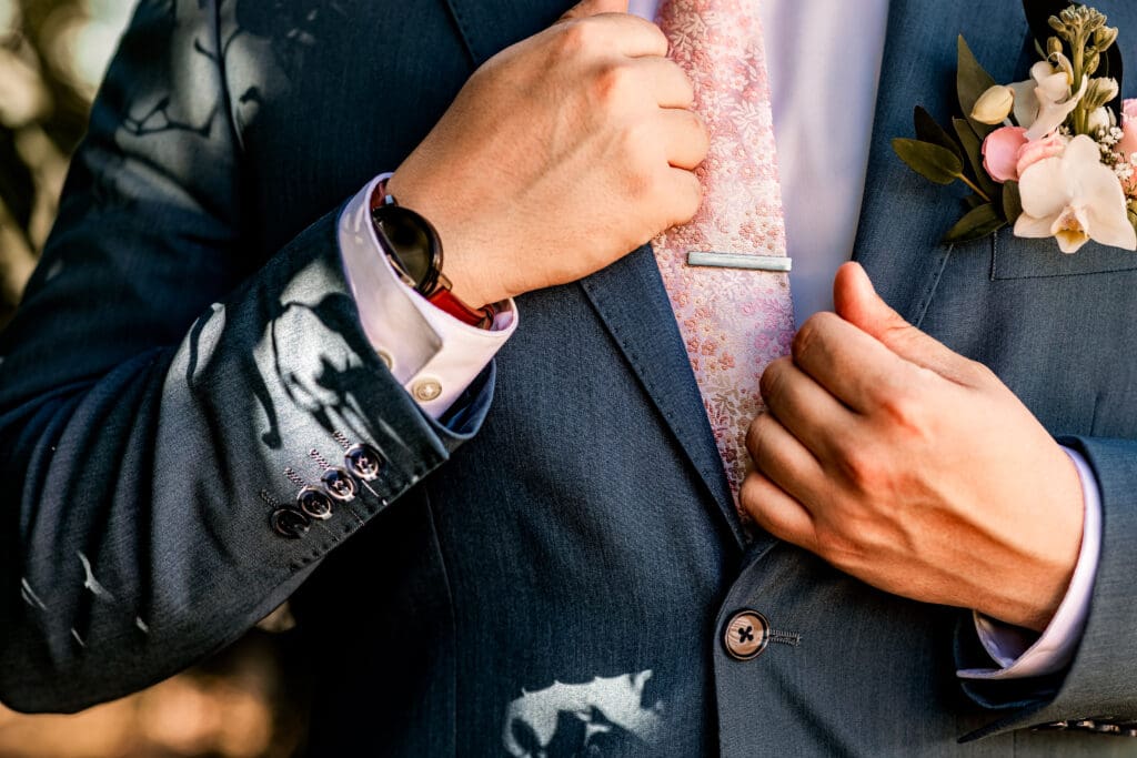 Close-up of Pittsburgh groom’s French blue suit cuff with Dogwood tree shadow at Phipps Botanical Gardens