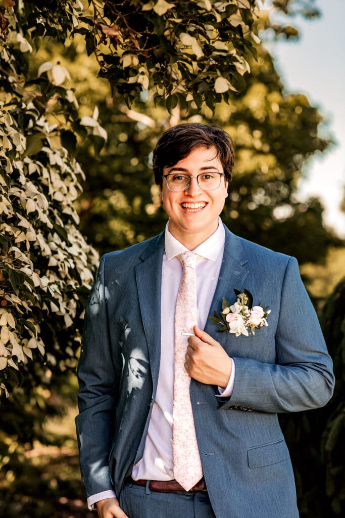 Pittsburgh groom smiling at the camera while standing under a Dogwood tree at Phipps Botanical Gardens