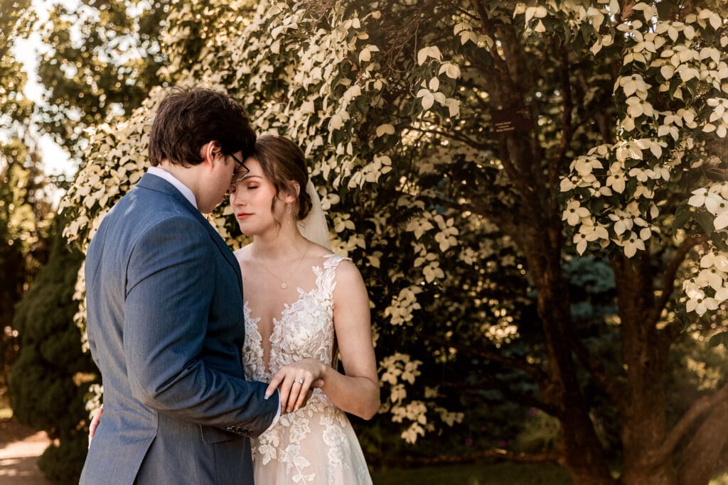 Pittsburgh bride and groom embracing under a Dogwood tree in the outdoor garden at Phipps Botanical Gardens