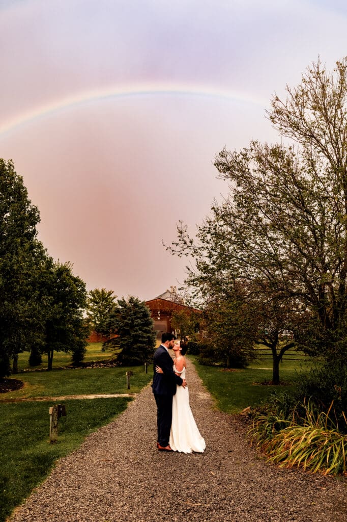 Bride and groom kiss beneath a rainbow during their Willowbrook wedding reception in Volant, PA