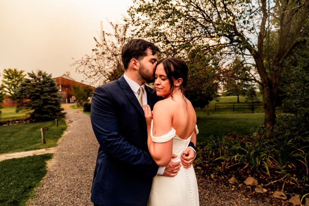 Pittsburgh couple shares a quiet embrace under a rainbow following their Willowbrook wedding ceremony in Volant, Pennsylvania