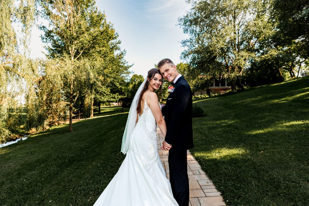 Wedding couple poses together on a lush garden path at Willowbrook