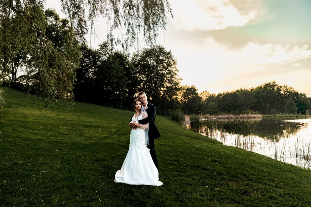 Wedding couple embraces near a tranquil pond at Willowbrook