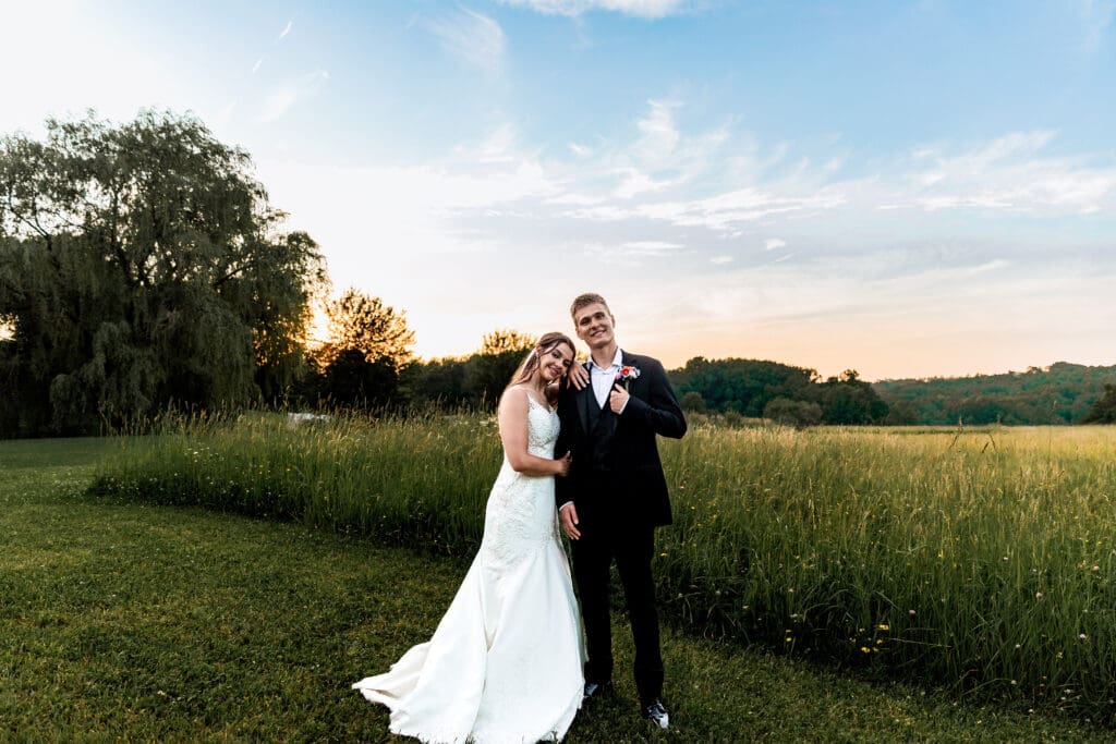 Couple poses on a grassy hill at sunset during their Willowbrook wedding