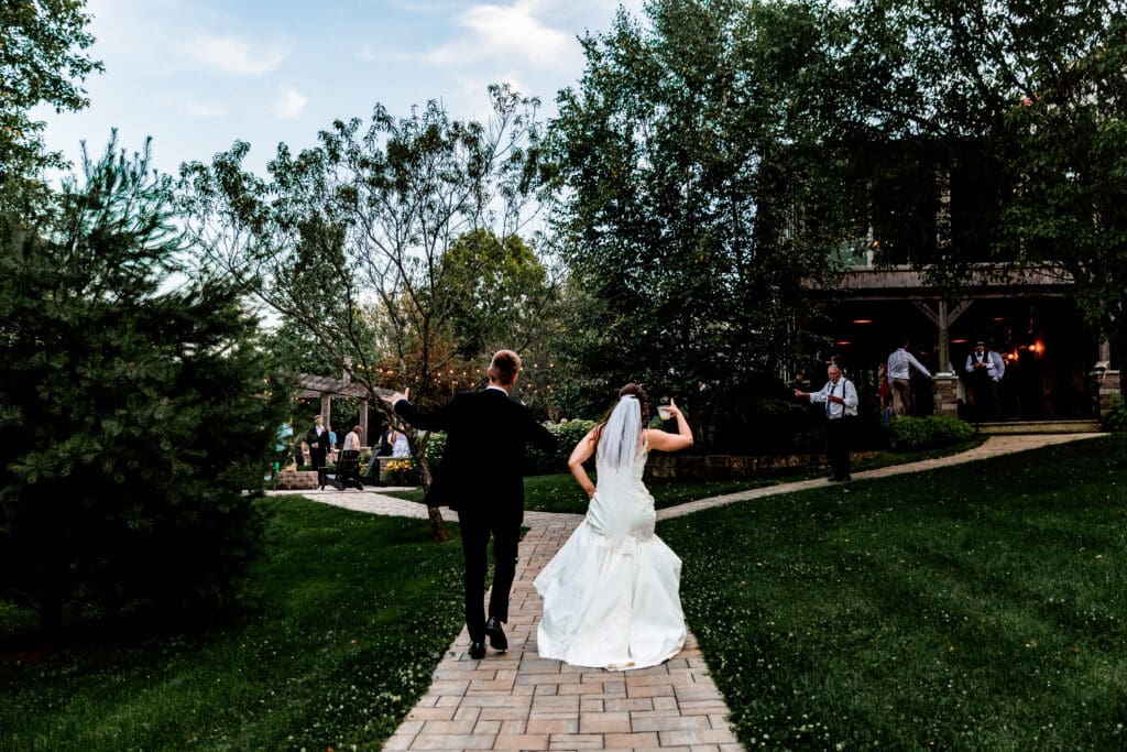 Bride and groom walk toward their outdoor reception at Willowbrook