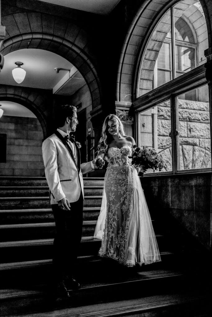 Groom helping his bride down the courthouse stairs after their wedding ceremony