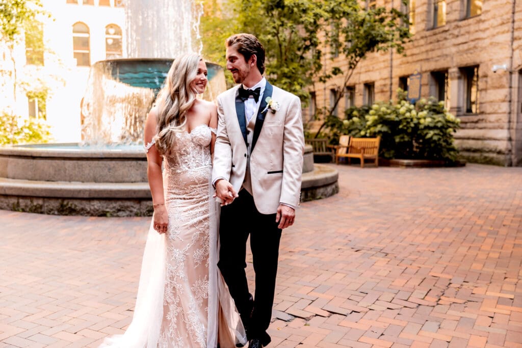 Wedding couple walking together in front of the fountain at Allegheny County Courthouse