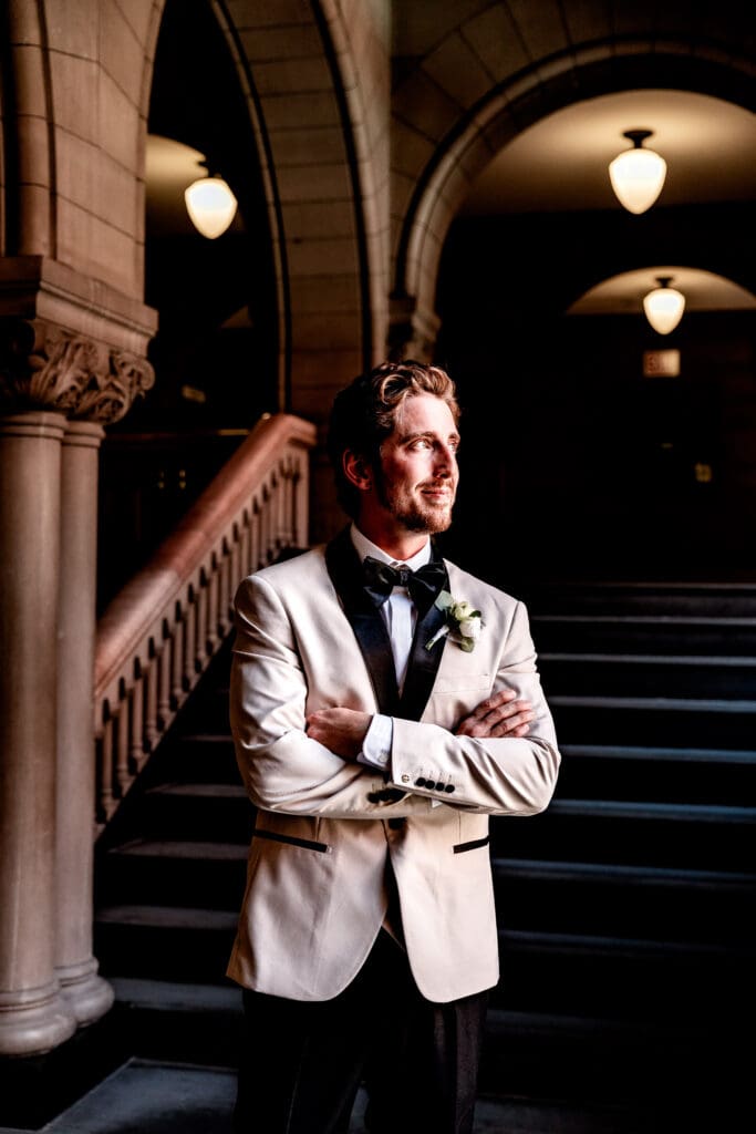 Groom standing by a courthouse window and reflecting before his Pittsburgh wedding ceremony at Allegheny County Courthouse