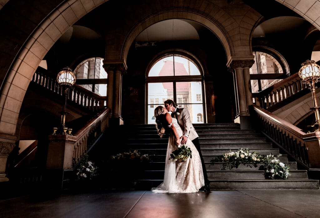 Wedding couple sharing a dip kiss on the grand staircase during an Allegheny County Courthouse elopement in Pittsburgh