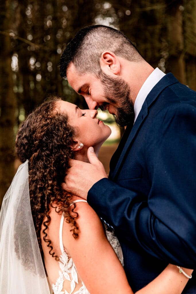 Bride and groom holding each other during sunset wedding portraits in the pine trees at Sanaview Farm