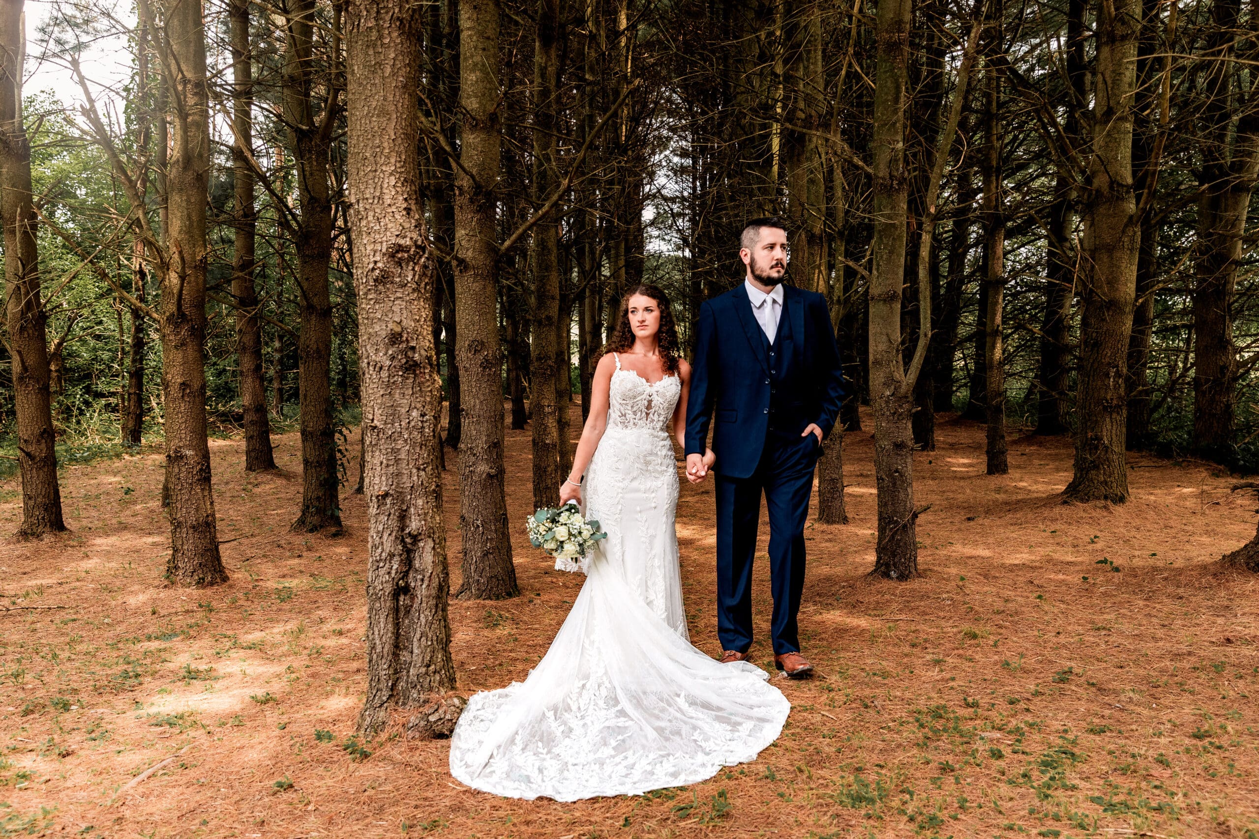 Bride and groom holding hands and embracing in a pine tree grove during their Sanaview Farm wedding in Somerset, PA