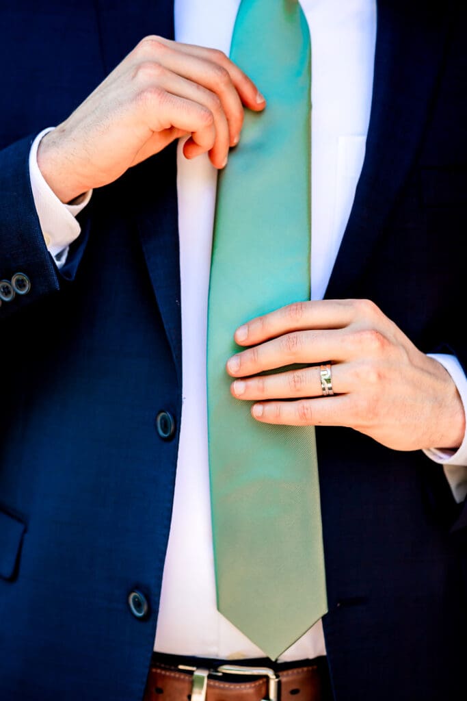 Close-up of groom’s suit jacket and green tie during a Schenley Park Welcome Center wedding