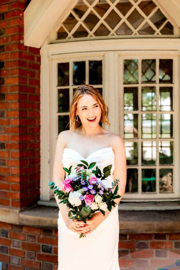Bride laughing and looking toward her groom during portraits at their Schenley Park Welcome Center microwedding