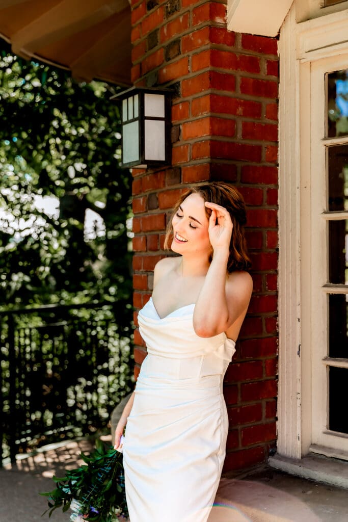Bride leaning against a wall and laughing during her Schenley Park Welcome Center wedding