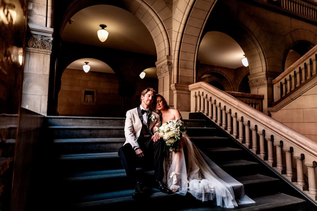 Wedding couple sitting together on the courthouse stairs after their Allegheny County Courthouse ceremony