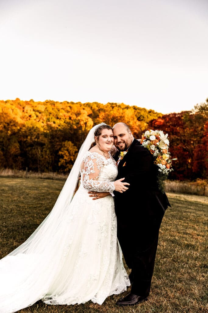 Bride and groom hold each other and smile at the camera during fall Ridgemont Farm wedding in Beaver County