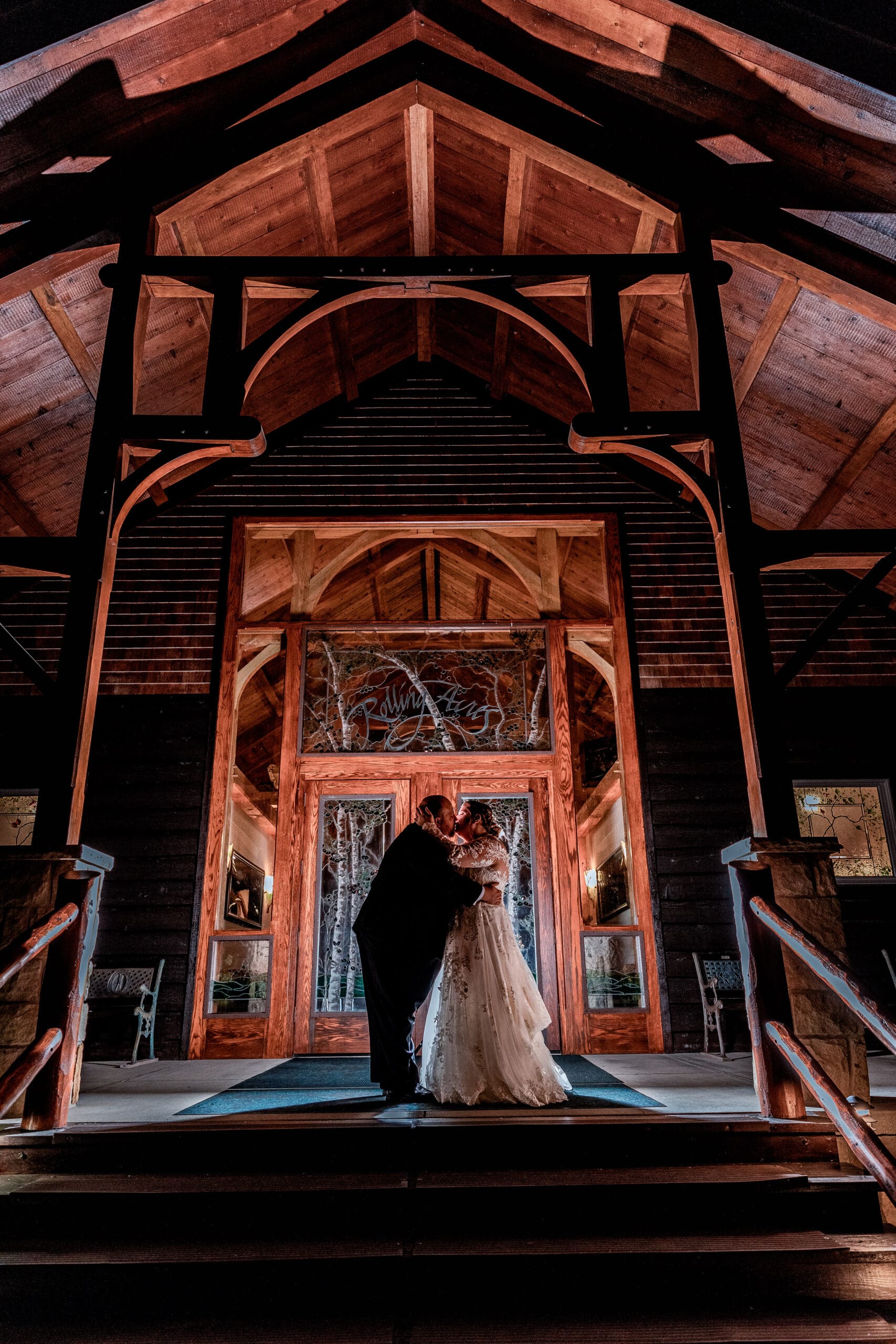 Pittsburgh bride and groom share a romantic embrace at the end of the night under the grand entrance of Timberhouse at Rolling Acres wedding reception, Beaver County micro wedding