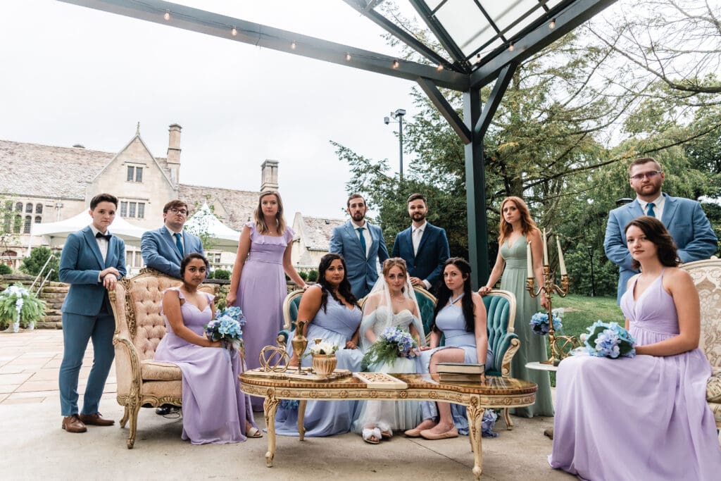 Wedding party in lavender dresses and blue suits gathers on an outdoor patio at Hartwood Acres