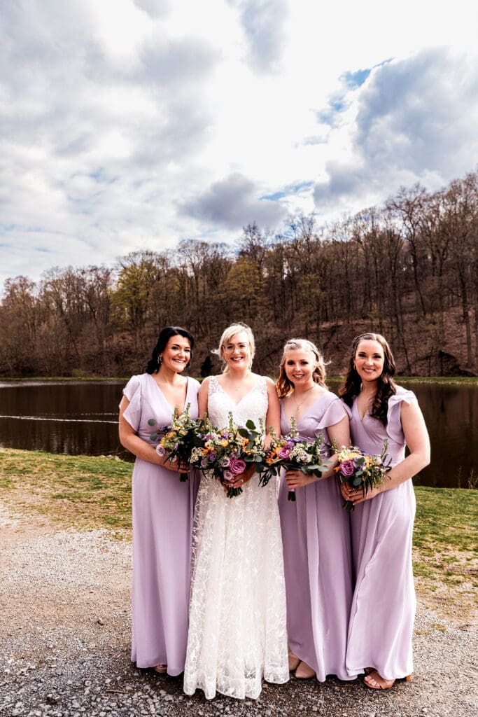 Line of bridesmaids in lavender dresses holding vibrant bouquets near The Fez