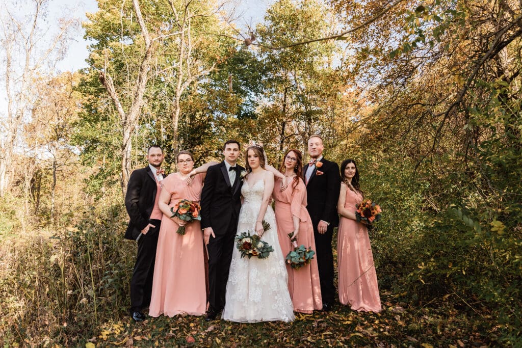 Bridal party poses in the woods with mixed sides during a Cozzi Acres wedding ceremony