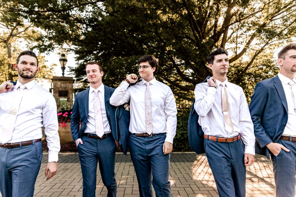 Pittsburgh groom and groomsmen walking toward the camera and looking at each other during pre-reception portraits at Phipps Botanical Gardens