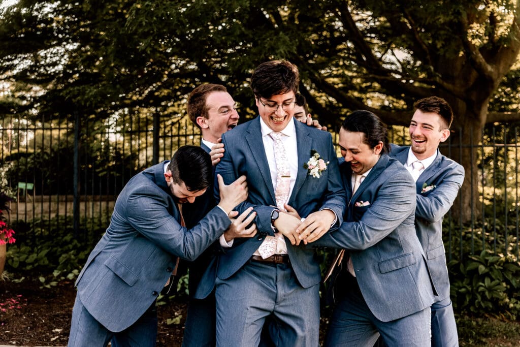 Pittsburgh groomsmen laughing and cheering to hype up the groom during pre-reception portraits at Phipps Botanical Gardens
