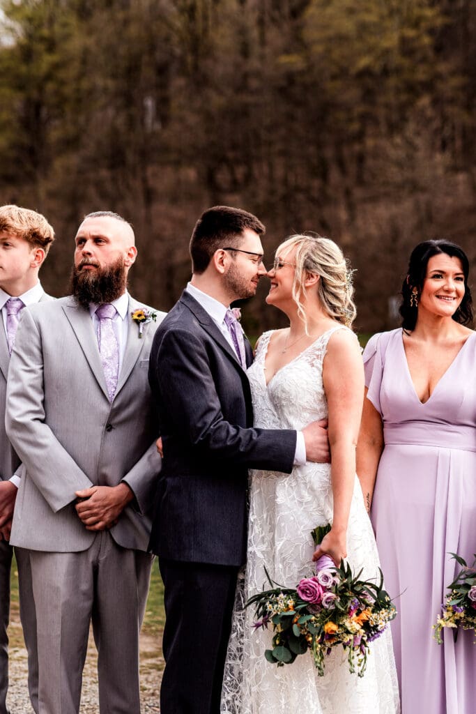 Wedding party in lavender dresses and white gown posing by a lake near The Fez in autumn