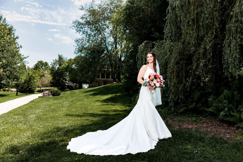 Bride holds colorful bouquet in an outdoor garden at Willowbrook
