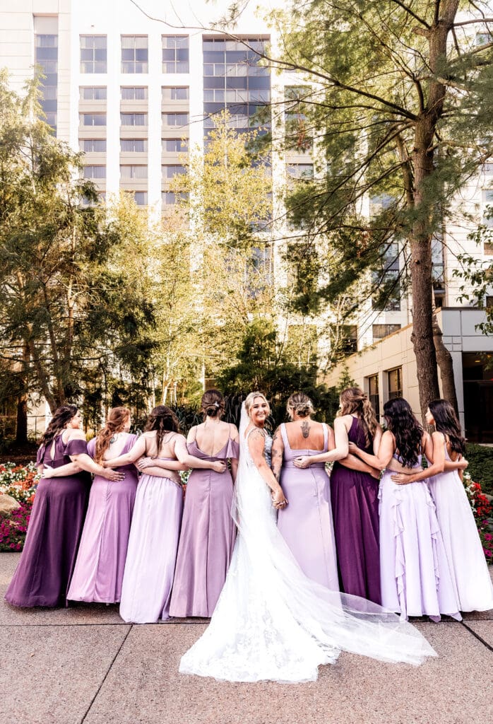 Bride and bridesmaids face away from camera with arms around each other at Pittsburgh Airport Marriott