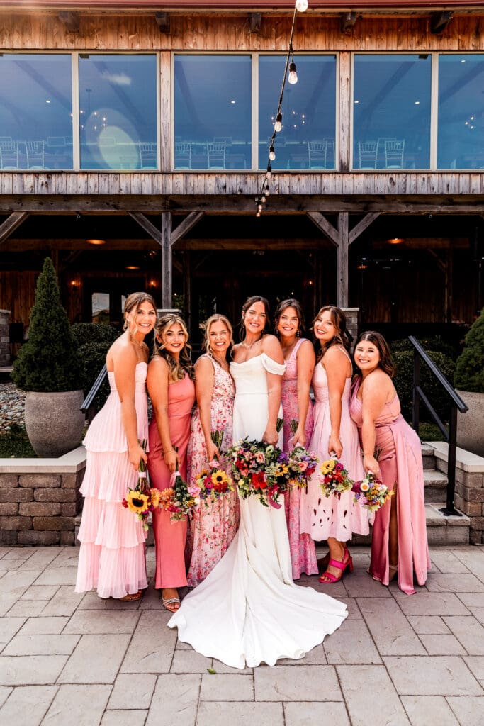 Bride and bridesmaids posing with bouquets in the Willowbrook reception barn courtyard in Volant, Pennsylvania