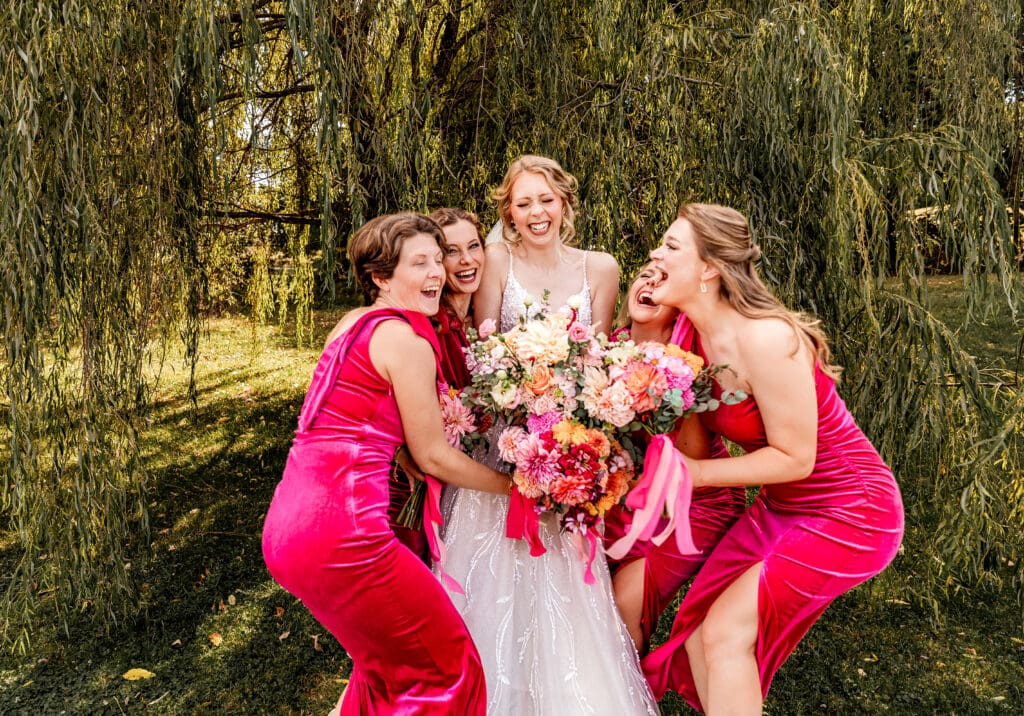 Bride being embraced by her bridesmaids under the willow tree at The Gathering Place at Darlington Lake wedding